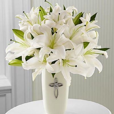 This striking display of pure white lilies will send your heartfelt expressions when words just aren't enough. Arranged in a white ceramic vase and enhanced by a cross, this arrangement is perfect for celebrations, confirmations, sympathy, weddings, or a special anniversary.This is an all-around arrangement.