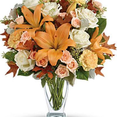 Capture the natural beauty of autumn with this stunning arrangement of lilies and roses in an elegant glass vase, sure to brighten any fall day.
This beautiful arrangement features white and peach roses, peach asiatic lilies and peach carnations and is finished with dusty miller, seeded eucalyptus, brown oak leaves and lemon leaf.