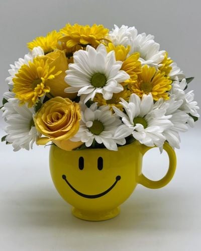 <p data-start="151" data-end="518">Sometimes the simplest gesture has the greatest impact—and <em data-start="210" data-end="221">Smile Mug</em> is pure sunshine in a cup. With cheerful yellow roses and soft white blooms arranged in an iconic smiley-face mug, this joyful bouquet is made to brighten anyone’s day. Whether you’re cheering someone up, saying thank you, or just sending a little love, this gift is guaranteed to deliver a grin.</p>
<p data-start="520" data-end="906">At the heart of the arrangement are radiant yellow roses, symbols of friendship, joy, and positivity. They’re complemented by crisp white flowers that soften the look and enhance the fresh, clean feel. The blooms are thoughtfully arranged in a reusable ceramic mug featuring a classic yellow smiley face—a keepsake that continues to spread happiness long after the flowers have bloomed.</p>
<p data-start="908" data-end="1328">This bouquet is ideal for all kinds of uplifting occasions. It's a wonderful “get well soon” gesture, a thoughtful pick-me-up for someone going through a rough patch, or a charming way to say “thinking of you.” It's also perfect for birthdays, thank-you gifts, or even as a fun surprise delivered to an office desk. With its cheerful vibe and compact size, it fits just about anywhere while filling the room with warmth.</p>
<p data-start="1330" data-end="1650">Rosa’s La Hacienda offers same-day delivery of this sunny bouquet across the Boca Raton area. Hand-arranged by our expert florists and delivered with care, <em data-start="1486" data-end="1497">Smile Mug</em> arrives fresh, fragrant, and ready to delight. As a local flower shop, we’re committed to helping you share joy in the moments that matter—big or small.</p>
<p data-start="1652" data-end="1747" data-is-last-node="" data-is-only-node="">Bright, fun, and full of good vibes, <em data-start="1689" data-end="1700">Smile Mug</em> is more than a bouquet—it’s a reason to smile.</p>